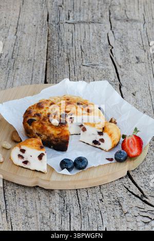 Runder Hüttenkäseauflauf mit Rosinen, Heidelbeeren und Erdbeeren auf Backpapier und Holzbrett, ein gesundes und köstliches Frühstück Stockfoto