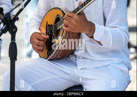 Ein Künstler bespannt geschickt ein Bouzouki, während er in leichter Kleidung auf Kreta, Griechenland, gekleidet ist. Stockfoto