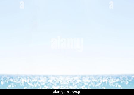 Die Ozeanoberfläche reflektiert Sonnenlicht auf sanften Wellen in flachem Design, blassblauem Himmel Stockfoto