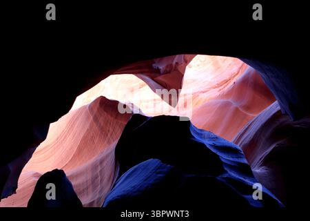 Sonnenlicht durchdringt die schmalen Sandsteinbögen des Antelope Canyon in Page Arizona und hebt wirbelnde rote und orangene Formationen hervor, die durch antike Erosion gemeißelt wurden. Stockfoto