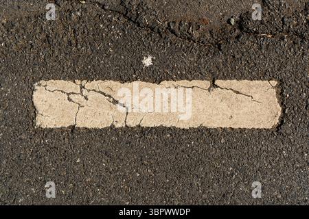 Weiße rechteckige Straßenmarkierung mit Rissen auf Asphalt Stockfoto