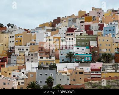 Las Palmas, Kanarische Inseln, Spanien - 13. März 2022. Farbenfrohe Gebäude kaskadieren einen Hügel hinunter und schaffen eine malerische Stadtlandschaft an einem bewölkten Tag. Stockfoto
