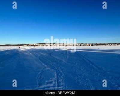 Eine weite Aufnahme eines schneebedeckten Feldes unter einem klaren, hellblauen Himmel an einem sonnigen Wintertag. Jämtland Schweden Stockfoto