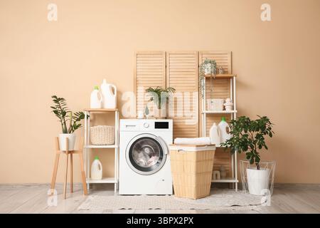 Stilvoller Waschraum mit moderner Waschmaschine, Korb, Regalen und Waschmittelflaschen Stockfoto