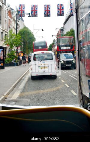 Oxford Street, berühmt für ihre Einkaufsmöglichkeiten im Zentrum von London aus an Bord eines Londoner Busses mit Union Jack Flaggen, die in London, England, Großbritannien, hängen Stockfoto