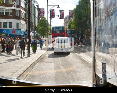Oxford Street, berühmt für ihre Einkaufsmöglichkeiten im Zentrum von London aus an Bord eines Londoner Busses mit Union Jack Flaggen, die in London, England, Großbritannien, hängen Stockfoto