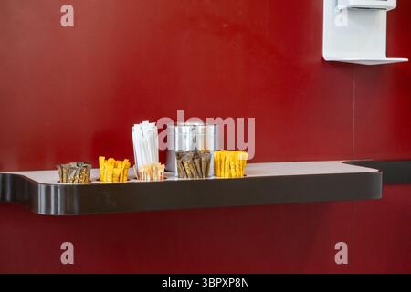 Posen, Polen - 18. Juni 2025: Ein ordentliches Arrangement verschiedener Kaffeezusatz, wie Zucker, Süßstoff und Rührstäbchen, auf einer modernen Cu-Theke Stockfoto