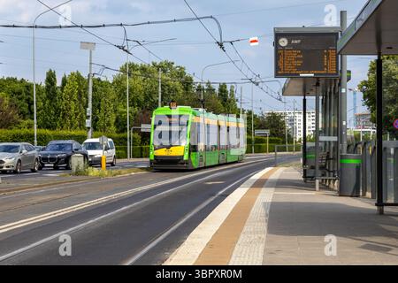 Posen, Polen - 18. Juni 2025: Blick auf eine moderne grüne elektrische Tramwaj auf der Route 18 nach Ogrody, vorbei an der AWF-Haltestelle, was für den öffentlichen Nahverkehr steht Stockfoto