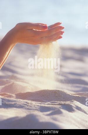 Strandsand rutscht durch die Hände der Frau Stockfoto