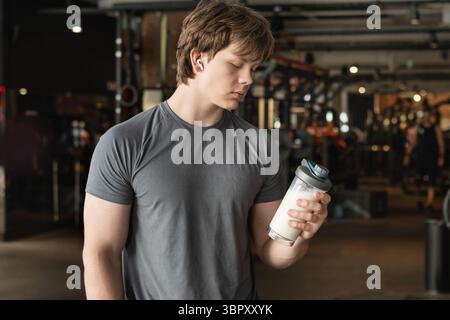 Porträt eines sportlichen kaukasiers oder Bodybuilders mit Proteinshake in der Hand. Sportler und Profi-Trainer mit Sportnahrungsgetränk während der Arbeit Stockfoto