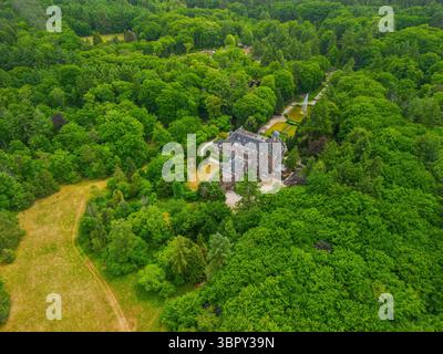 Ein Blick aus der Vogelperspektive auf ein historisches Herrenhaus, umgeben von üppigen grünen Bäumen und einem wunderschön gestalteten Garten mit Brunnen, Wanderwegen und Parkplatz Stockfoto
