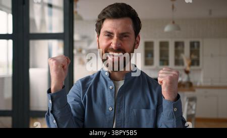 Glücklicher glücklicher Kaukasier Mann Gewinner Dad lächelnd geballte Fäuste männlicher Gewinn Freude zu Hause Erfolg Aufregung glückliche Eltern schreien ja Gefühl Stockfoto