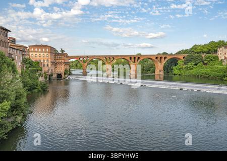 Panoramablick auf ein Wehr des Flusses Tarn vor der Backsteinbogenbrücke Pont du 22 aout 1944 und die Backsteinarchitektur des Viertels La M Stockfoto