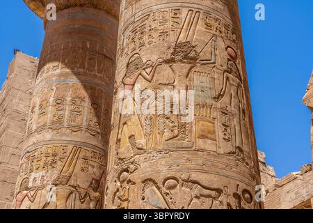 Hieroglyphen auf den Säulen in der Großen Hypostilhalle des Tempelkomplexes Karnak in Luxor, mit Darstellungen des alten ägyptischen Gottes Min. Stockfoto