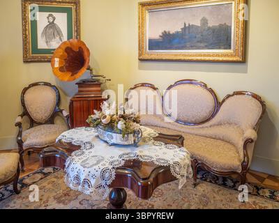 Ein Wohnzimmer in der erhaltenen Wohnung in der Casa Milà (La Pedrera), mit antiken Möbeln und einem Vintage Horngramophon, Barcelona, Spanien. Stockfoto