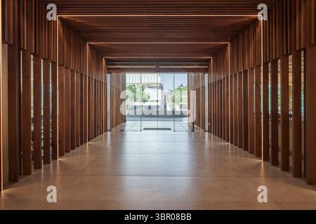 Symmetrischer Blick auf einen modernen Korridor mit Holzlatten und warmer LED-Beleuchtung. Stockfoto