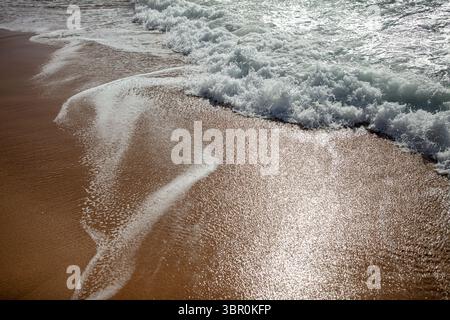 Schäumende Ocean Wave, Die Über Sandy Beach Gespült Wird Stockfoto