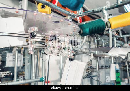 Spanner mit farbigen Gewinden, die sich an den Schiebern der Maschinen befinden. Industrieunternehmen zur Herstellung von Socken. Detailansicht Stockfoto