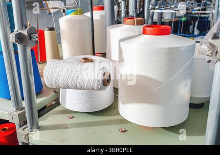 Weiße Gewinde auf den Schiebern bei Maschinen. Industrieunternehmen zur Herstellung von Socken. Moderne Technologien Stockfoto