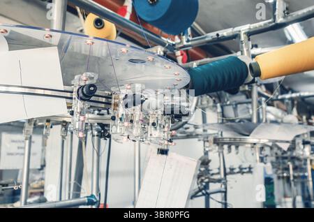 Gewindespanner befinden sich an den Schiebern der Maschinen. Industrieunternehmen zur Herstellung von Socken. Detailansicht Stockfoto