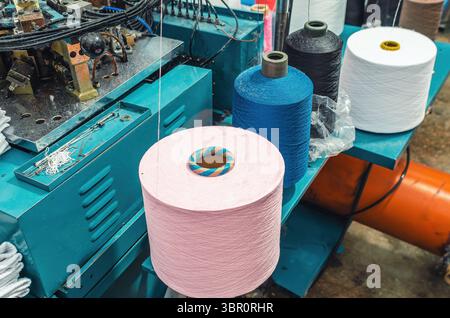 Draufsicht der farbigen Gewinde auf den Schiebern an Maschinen. Industrieunternehmen zur Herstellung von Socken. Moderne Technologien Stockfoto