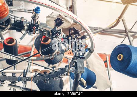 Ansicht von unten auf farbigen Gewinden auf den Schiebern bei Maschinen. Industrieunternehmen zur Herstellung von Socken. Moderne Technologien. Stockfoto