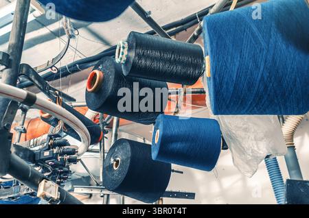Farbige Gewinde auf den Schiebern bei Maschinen. Industrieunternehmen zur Herstellung von Socken. Moderne Technologien Stockfoto