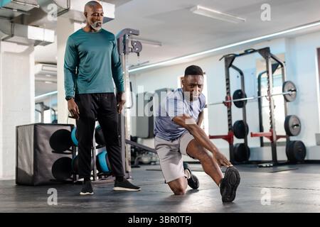 Afroamerikanischer Trainer und Kunde, der Ausfallschritt im Fitnessstudio mit Hockgestell und Kopierraum macht. Fitness, Training, Kraft, Workout, Bewegung, Sport, Mo Stockfoto