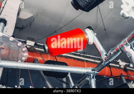 Ansicht von unten auf farbigen Gewinden auf den Schiebern bei Maschinen. Industrieunternehmen zur Herstellung von Socken. Moderne Technologien. Stockfoto