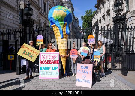 Mitglieder der Mütter protestieren vor der Downing Street in London mit einem riesigen, planetenförmigen Eiskegel, der die Regierung auffordert, die Erschließung des Ölfeldes in Rosebank abzulehnen und die Expansion der Öl- und Gasförderung in der Nordsee zu stoppen. Die Demonstration fällt mit der Veröffentlichung eines Berichts zusammen, der den vom Menschen verursachten Klimawandel mit verstärkten Hitzewellen in ganz Europa in Verbindung bringt, so die Gruppe. Stockfoto