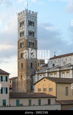 Glockenturm der Kathedrale San Martino in Lucca, Italien, romanisch-gotischer Stil mit weißem und steinernem Muster, von Laub eingerahmt. Stockfoto