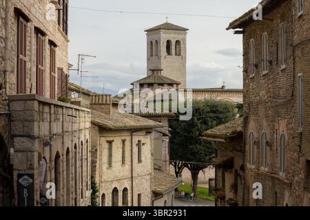 Blick auf den Glockenturm der Kirche St. Peter in Assisi, Italien, umgeben von mittelalterlichen Gebäuden und engen Gassen. Stockfoto