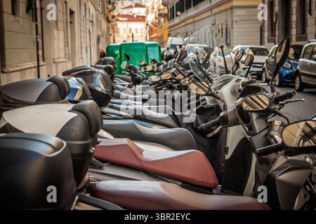 Geparkte Motorroller füllen eine enge Einbahnstraße in Triest, Italien. Polierte Spiegel, Ledersitze und Top Boxen bilden ein dichtes Muster, während sie klein sind Stockfoto