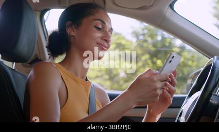 Afroamerikanische Frau hält mit Handy Smartphone online Lächeln Netzwerk soziale Medien Nachrichten Technologie Geschäftsfrau weibliches Auto Stockfoto