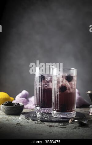Erfrischende Blackberry Lemonade mit Eis in Kristallgläsern auf grauem Hintergrund Stockfoto
