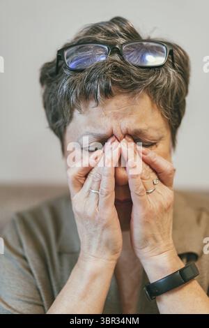 Nahaufnahme der älteren Dame fühlen sich ungesund Touch Massage Augen mit starken Migränesymptomen oder Kopfschmerzen, ältere Frau nehmen Brillen, die an d leiden Stockfoto