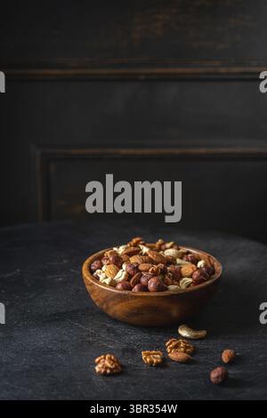 Gemischte Nüsse in einer Schüssel auf dunklem hölzernem Hintergrund Stockfoto