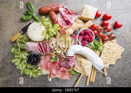 Mix aus verschiedenen Snacks und Vorspeisen. Spanische Tapas oder italienischen Wein auf einer Holzplatte. Tapas Bar. Nüsse, Oliven, Wurst, Käse, Schinken, Tomaten Stockfoto