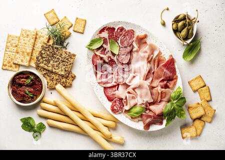 Vorspeisen mit verschiedenen Antipasti, Wurstwaren, Snacks und Rotwein auf weißem Hintergrund. Wurst, Schinken, Tapas, Oliven und Cracker für eine Buffetparty. Stockfoto
