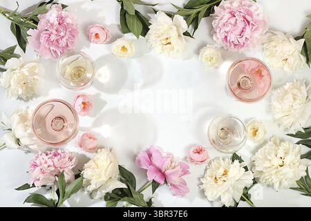 Blumenkomposition mit verschiedenen Sorten von Rosenwein, Sommer alkoholischer Cocktail für eine Party und Pfingstrose Blumen auf einem hellen Hintergrund, das Konzept o Stockfoto