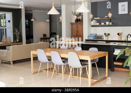 Esstisch aus Holz mit sechs grauen Stühlen in offenem Wohn- und Essbereich mit Kücheninsel Stockfoto