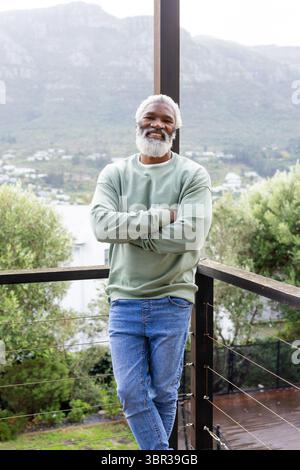 Afroamerikaner Senior-Mann mit grünem Sweatshirt, der an Deck am Geländer mit Blick auf das Tal steht Stockfoto