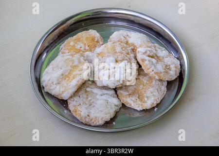 Leckere Khaja süß auf einer Stahlplatte mit hölzernem Hintergrund. Dieser in Zuckersirup getränkte, frittierte Teig, auch bekannt als Gaja oder Chiroti, ist ein beliebtes T-Shirt Stockfoto