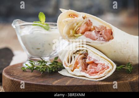 Frische Tortilla Wrap mit Gemüse und Lachs auf Holz Schneidebrett Stockfoto