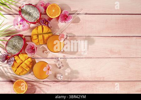 Sonniges tropisches Banner, Hintergrund mit Cocktails und Säften aus Zitrusfrüchten, Drachenfrüchten und Mango. Exotische Früchte und Orchideenblüten auf einem hellen Hintergru Stockfoto