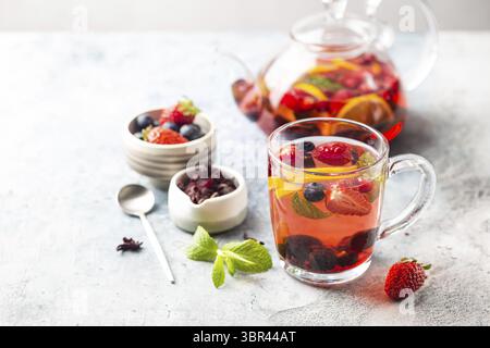Fruchtroter Tee mit Beeren in Glasbecher auf weißem Hintergrund Stockfoto
