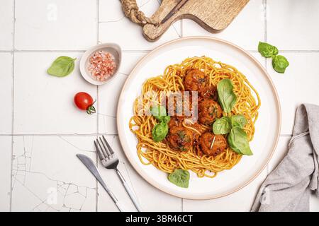 Spaghetti-Pasta mit Fleischbällchen und Tomatensauce auf einem Teller mit weißem Hintergrund, Blick von oben Stockfoto