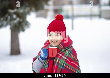 Glückliches Mädchen mit heißem Kakao, Schokolade oder Tee. Aktivitäten für Kinder am Wintertag. Urlaubskonzept Stockfoto