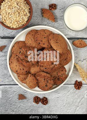 Frisch gebackene hausgemachte Haferflockenkekse mit Schokoladenchips und glutenfreien Nüssen mit Ohren auf Betonhintergrund, moderne Bäckerei und Getreidezubereitungen Stockfoto
