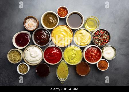 Set aus verschiedenen Schüsseln mit verschiedenen Dip-Saucen, auf dunklem Hintergrund, Draufsicht Stockfoto